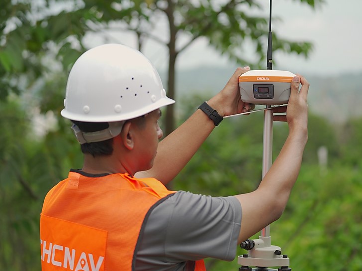Surveyor using CHCNAV i85 GNSS receiver in the field for land surveying.