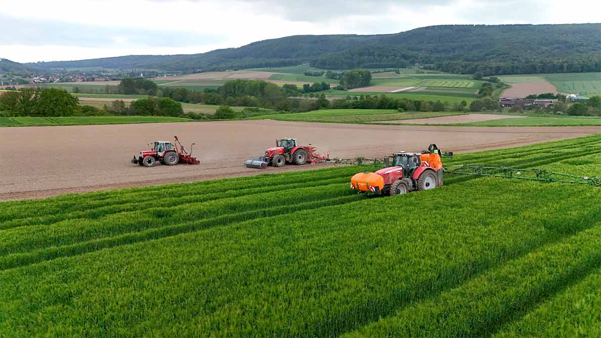 Aerial view of multiple CHCNAV-equipped tractors performing precision farming operations in a green agricultural field